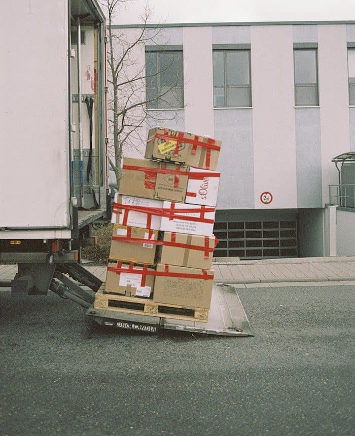 Securely taped cartons stacked on a trolley beside a moving truck
