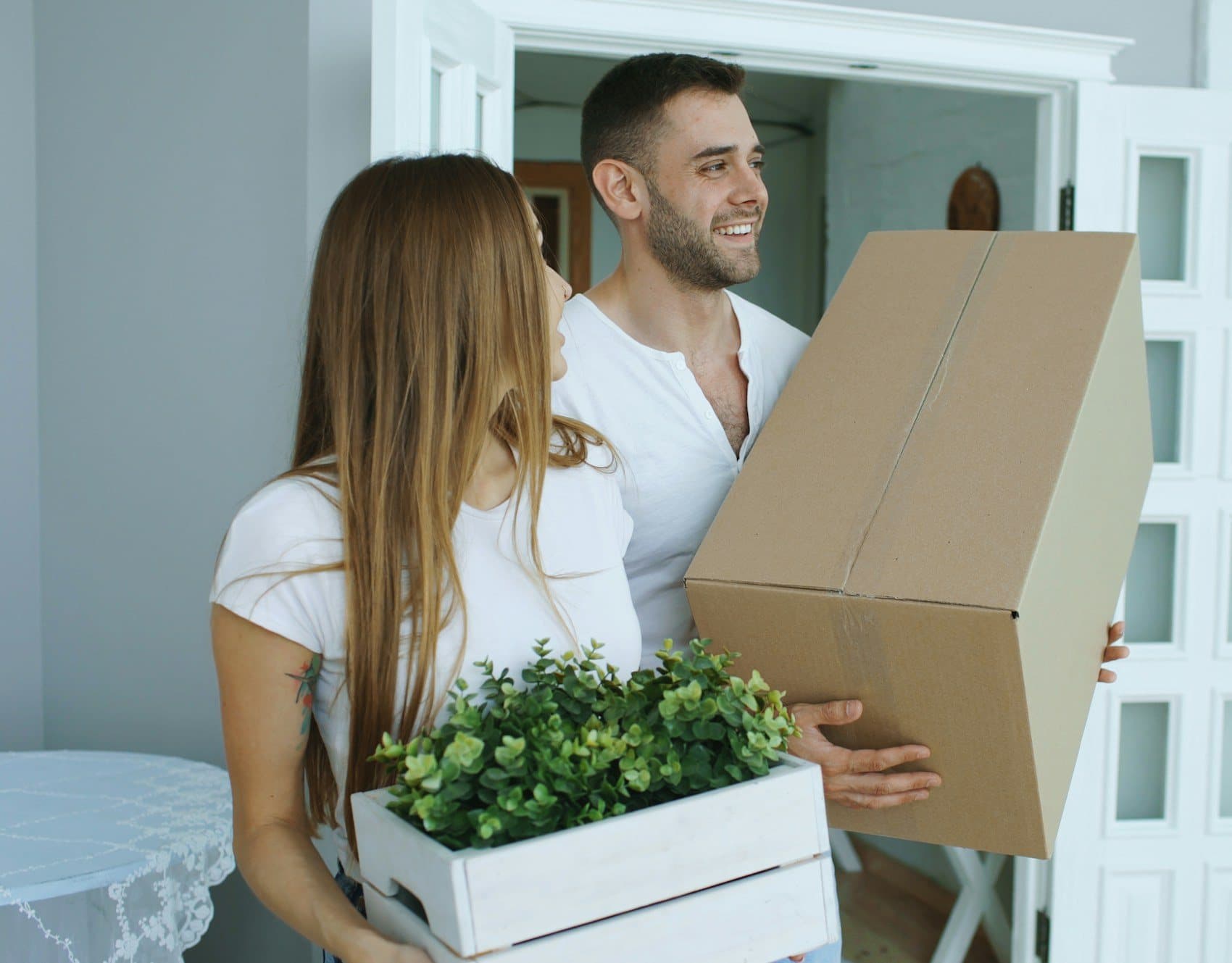 Happy couple carrying moving boxes into their new home after house shifting